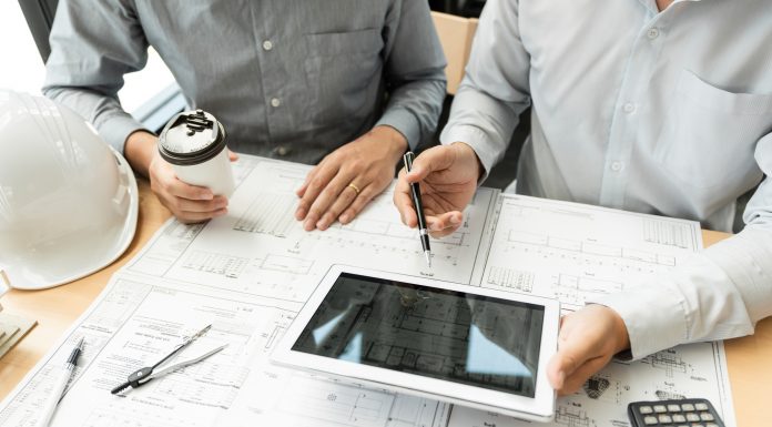 Two engineer and architect discussing blueprints data working and digital tablet
