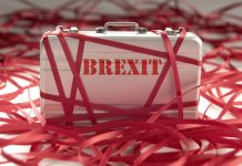 Suitcase with Brexit written on covered in red tape