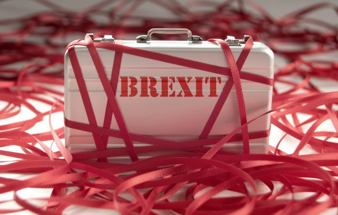 Suitcase with Brexit written on covered in red tape