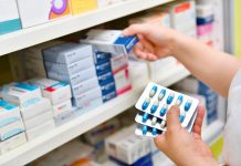 Pharmacist holding medicine box and capsule pack in pharmacy drugstore