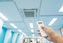 person controlling air conditioning in hospital with remote - Climate-smart healthcare