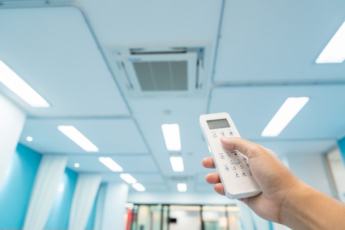 person controlling air conditioning in hospital with remote - Climate-smart healthcare