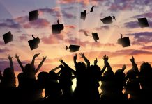 Graduates throwing hats into air against sunset, graduates apprentices and interns