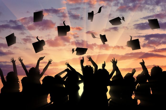 Graduates throwing hats into air against sunset, graduates apprentices and interns
