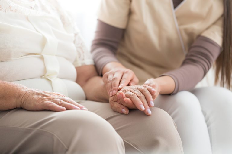 Close-up of nurse taking care about elderly person