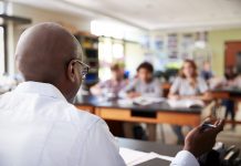 High School Tutor At Desk Teaching Student