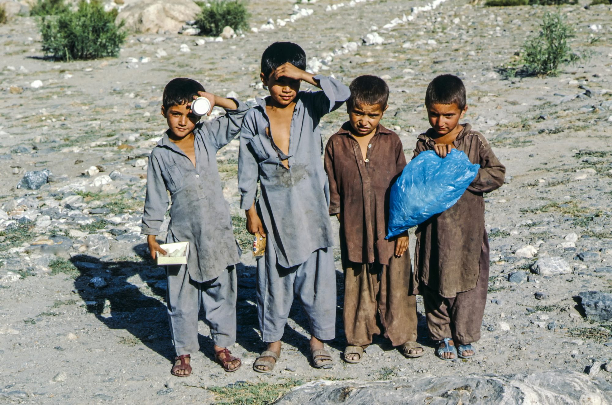 Children pose in dusty landscape at the Karakoram Hwy near Gilgit, Pakistan