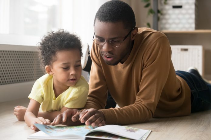 father and toddler son reading book together