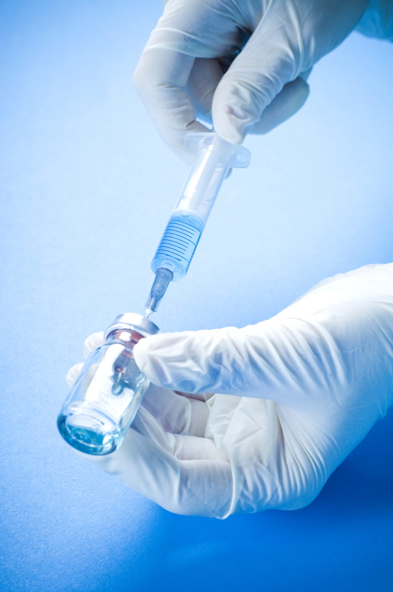A doctor extract a vaccine dose using a syringe
