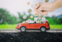 Person putting coins into toy car to symbolise saving up for an electric vehicle