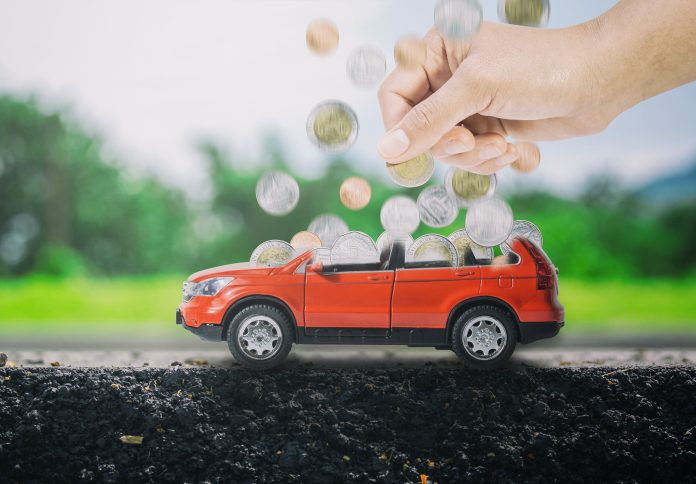 Person putting coins into toy car to symbolise saving up for an electric vehicle