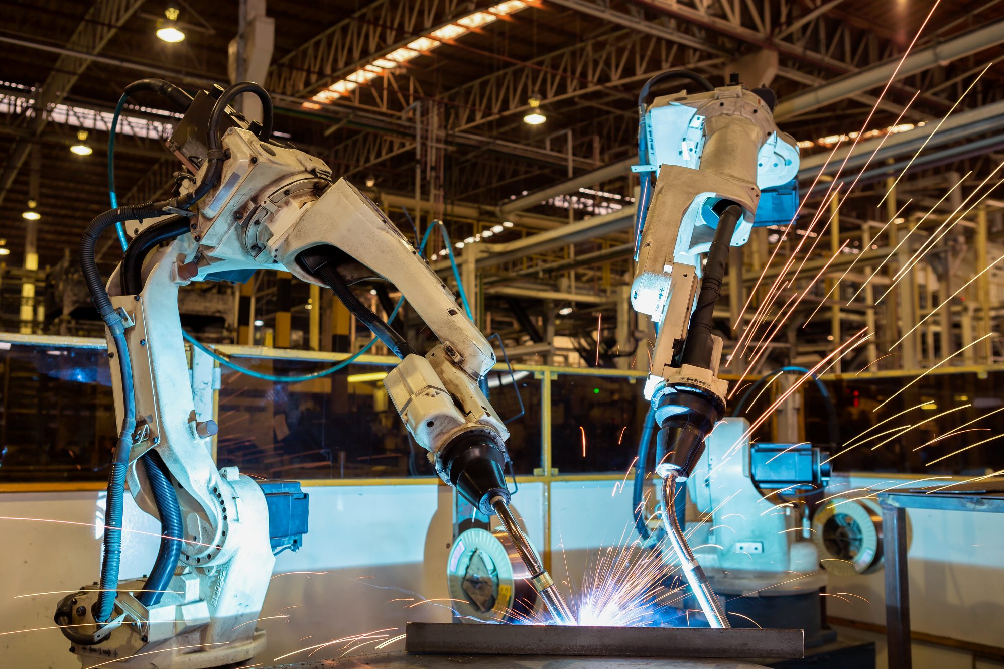 Team robots are welding assambly part in automotive industrial factory