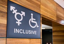Inclusive public bathroom sign on wooden pannelling