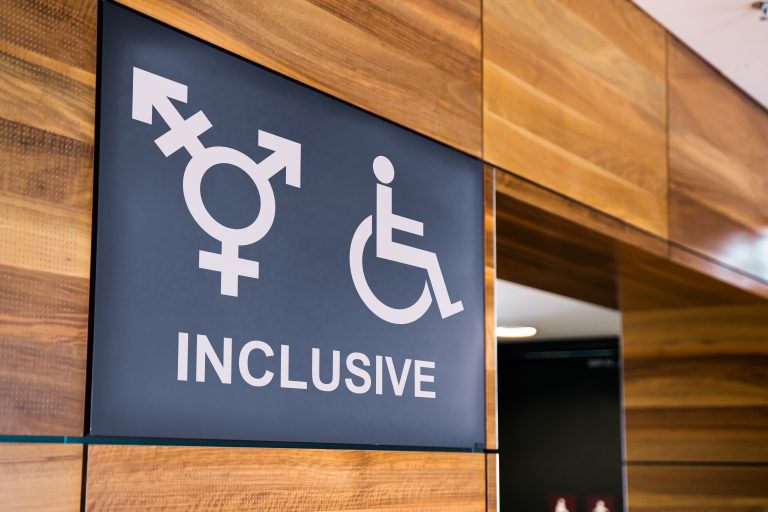 Inclusive public bathroom sign on wooden pannelling