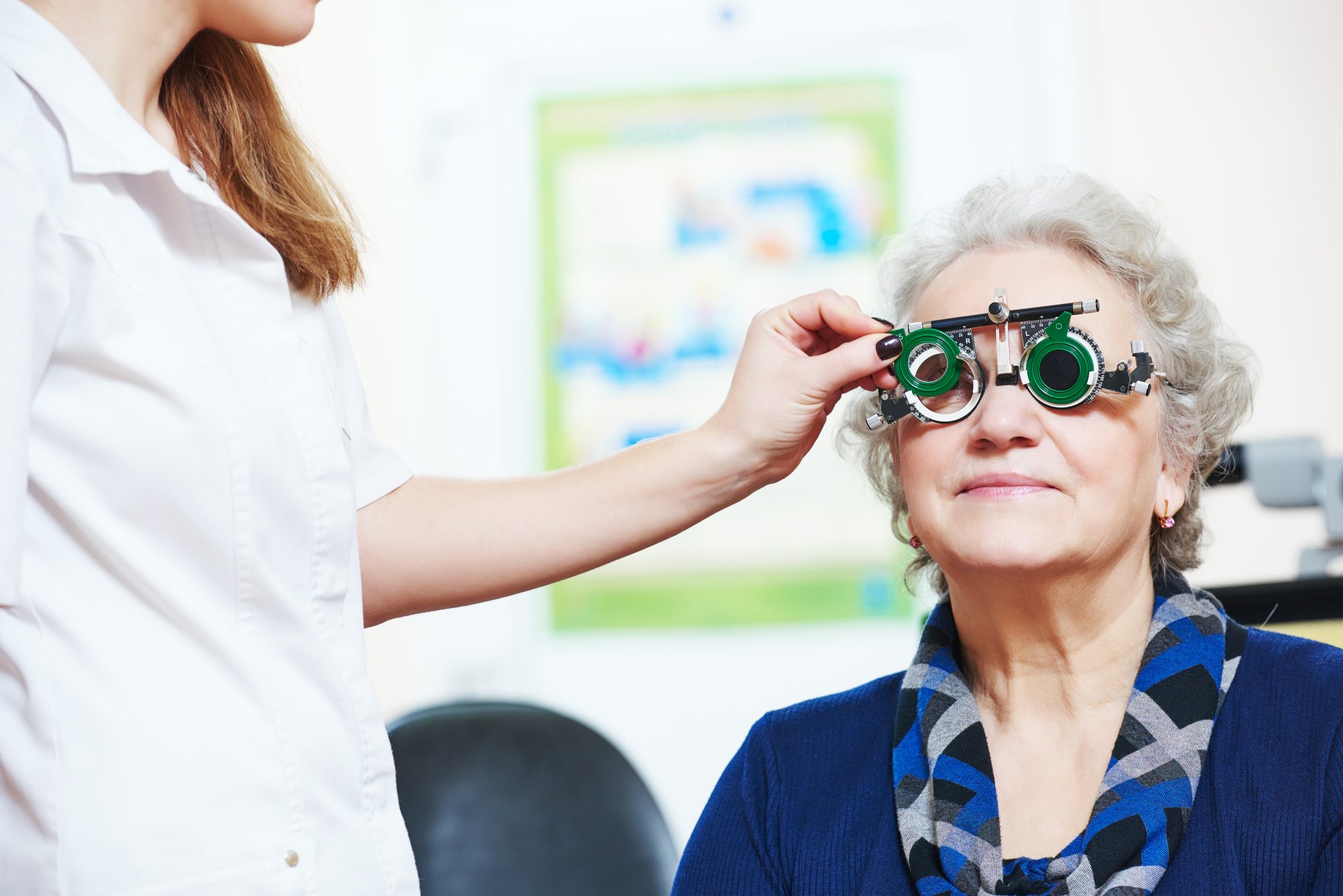 Optometry. female doctor ophthalmologist or optometrist examines senior woman eye sight with phoropter in clinic