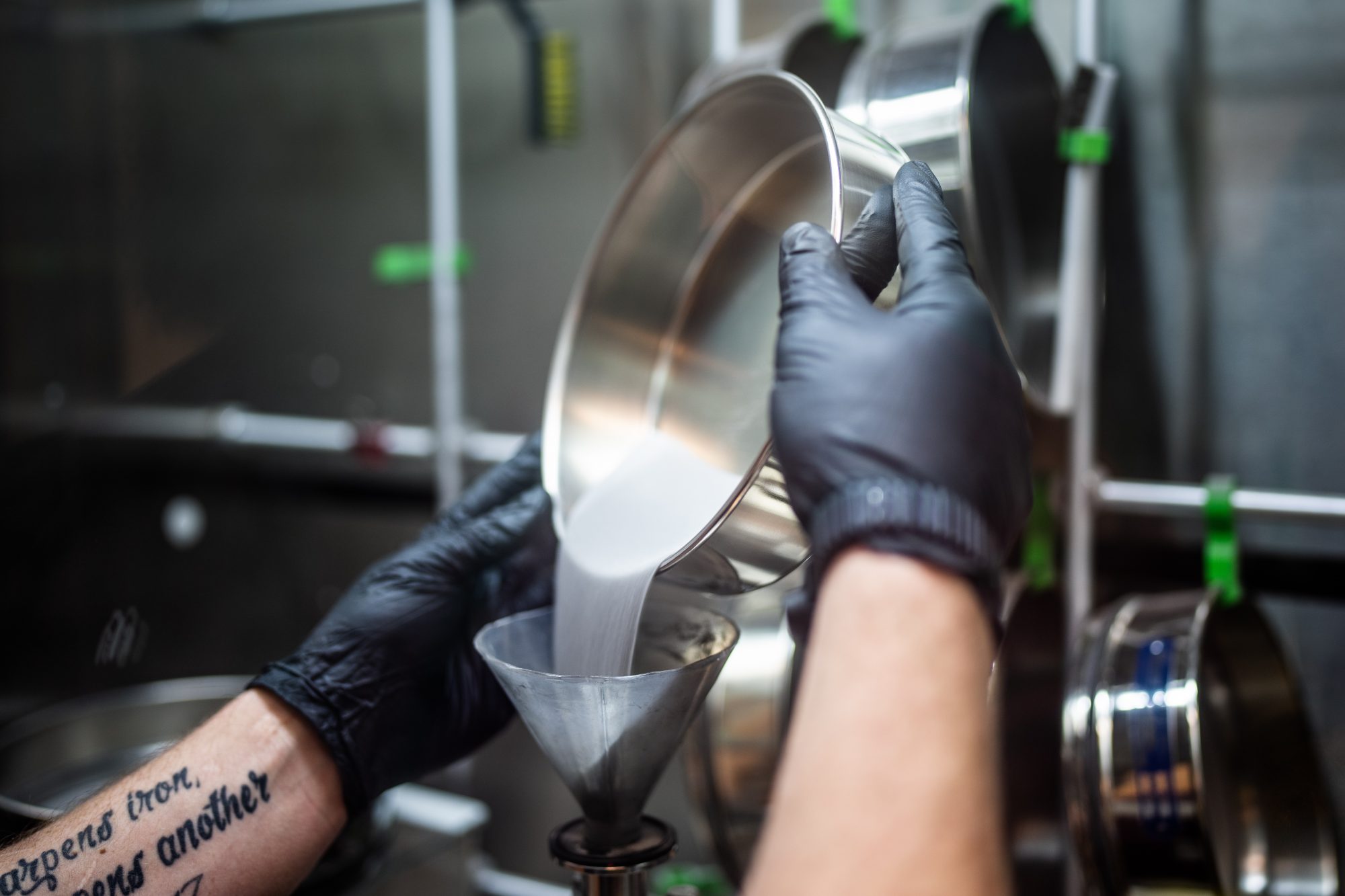 Levi Van Bastian fills a hopper with rammaterial to print on the LENS machine on Dec. 21, 2022, allowing the ability to test 3D print new superalloys.