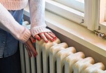 woman touching radiator indicating energy crisis problems