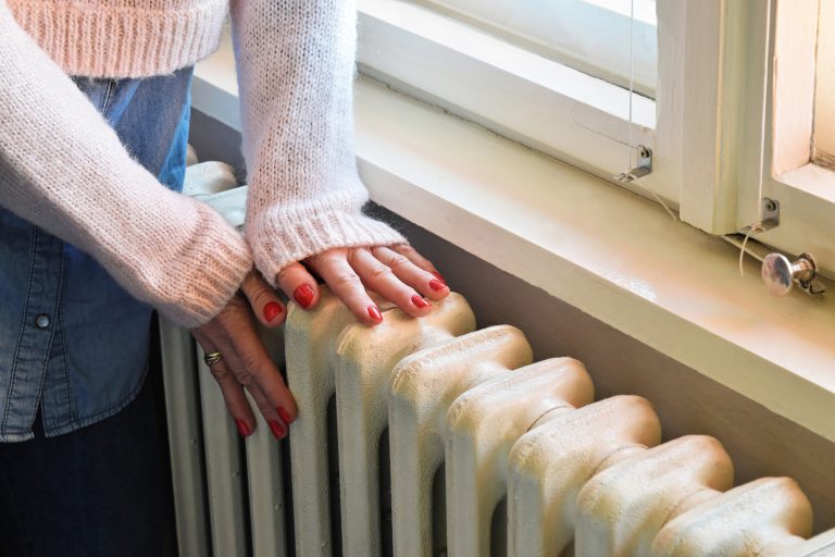 woman touching radiator indicating energy crisis problems