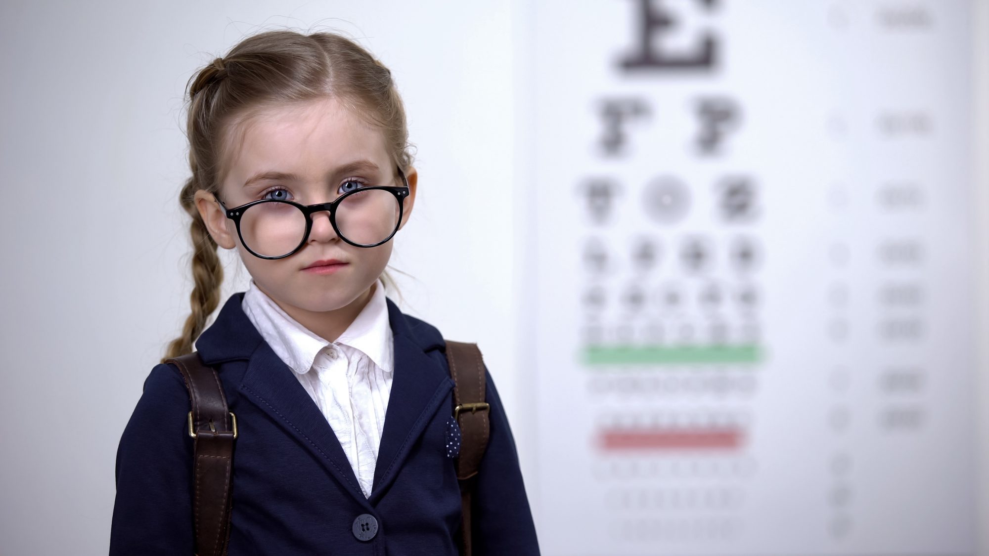 schoolgirl looking over glasses, serious child with good vision, correction