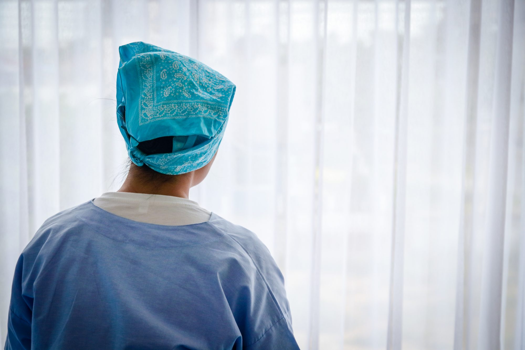 A female cancer patient looking at the window.