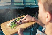 Person throws kitchen food waste into compost heap to make organic fertilizer. Composting - eco-friendly recycling technology