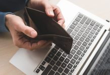 Man holding an empty wallet over computer because he lost his money to a fraudster