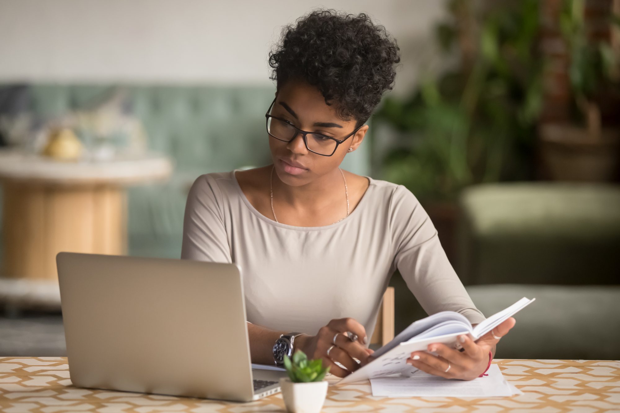 Student looking at laptop holding book doing research