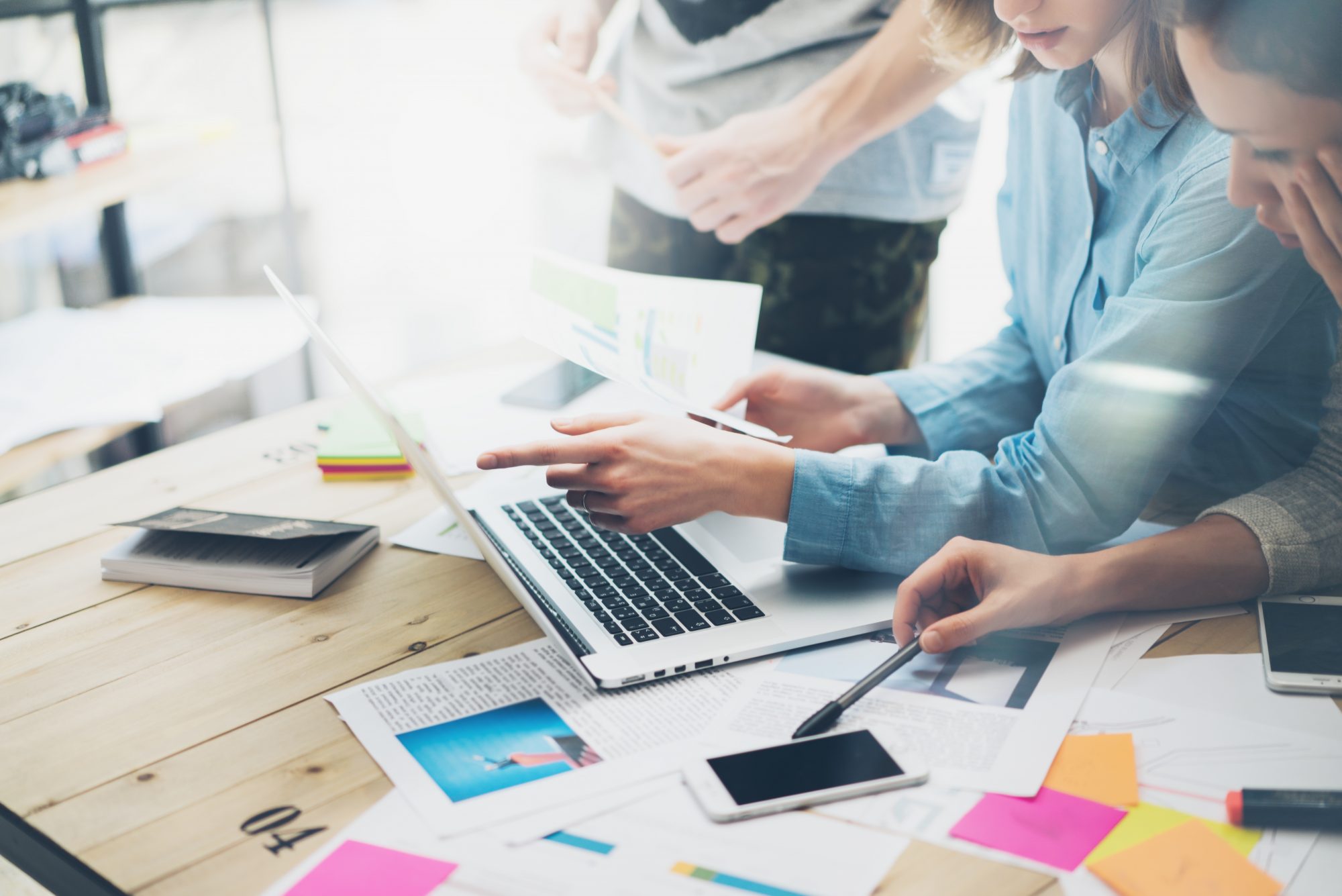 Creative team coworking project.Photo business managers working with new startup in modern loft.Analyze reports,plans. Notebook on wood table, papers, documents, statistics.