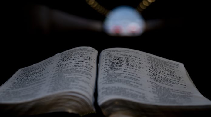 Close-up of Holy Bible open in tunnel. Background with yellow, red and blue lights.