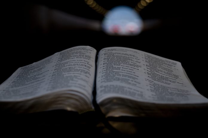 Close-up of Holy Bible open in tunnel. Background with yellow, red and blue lights.