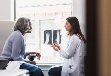 A serious female orthopedic doctor shows a senior female patient an x-ray of the patient's fractured foot.