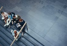 High angle view of university students sitting on stairs and discussing studies. Young people studying in college campus.