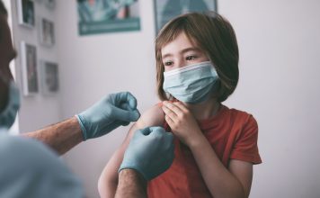 Doctor putting adhesive bandage to a child after Covid-19 vaccine injection.