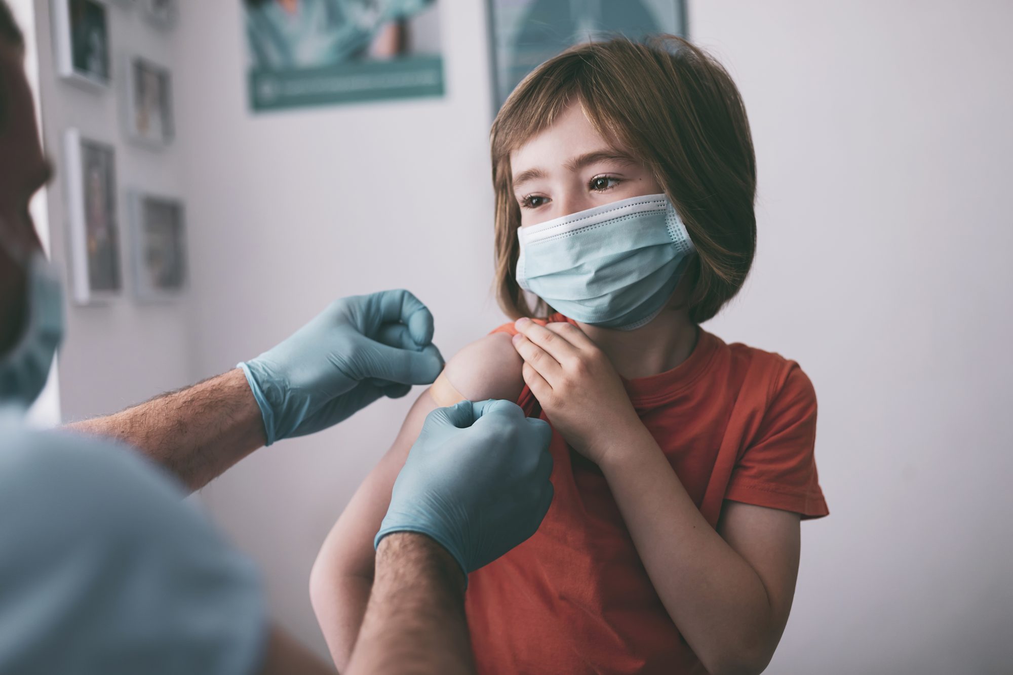 Doctor putting adhesive bandage to a child after Covid-19 vaccine injection.