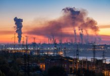 Industrial landscape of plant pipes producing toxic smoke with air pollution in the sky on sunset, hydroelectric dam and high voltage towers, Zaporizhzhia, Ukraine, EU