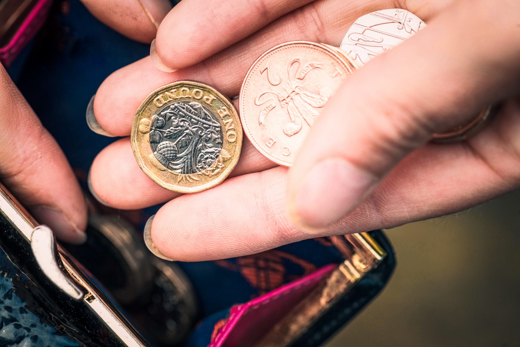 Close-up of a woman's hand as she counts the remaining change left in her purse.