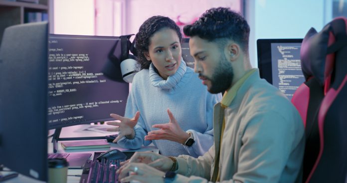 Computer, woman programmer and man training for coding, cyber security or software on computer. Female IT specialist, male coder or talking to connect internet, information update and cloud computing