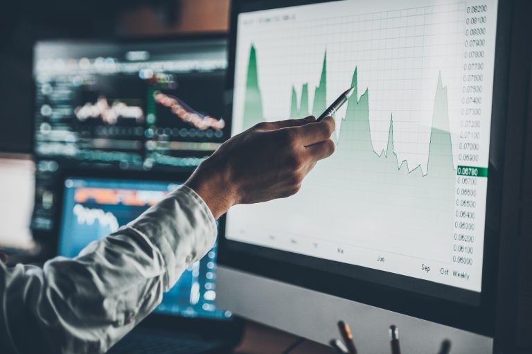 Close-up of young businessman pointing on the data presented in the chart with pen while working in creative office