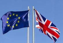 European Union flag and flag of UK on flagpole in front of blue sky