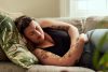 Shot of a young woman suffering from stomach cramps on the sofa at home