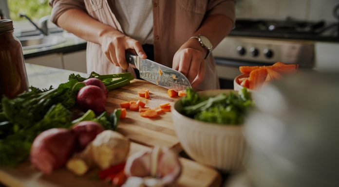 Female hands cutting vegetables on cuttiing board - woman preparing a healthy meal to boost the immune system