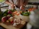 Female hands cutting vegetables on cuttiing board - woman preparing a healthy meal to boost the immune system