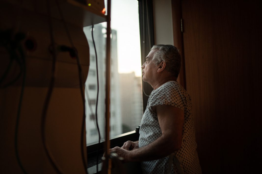 Senior patient looking through window at hospital