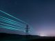 Electricity transmission towers with glowing wires against the starry sky