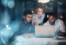 Cropped shot of three young businessmpeople working together on a laptop in their office late at night