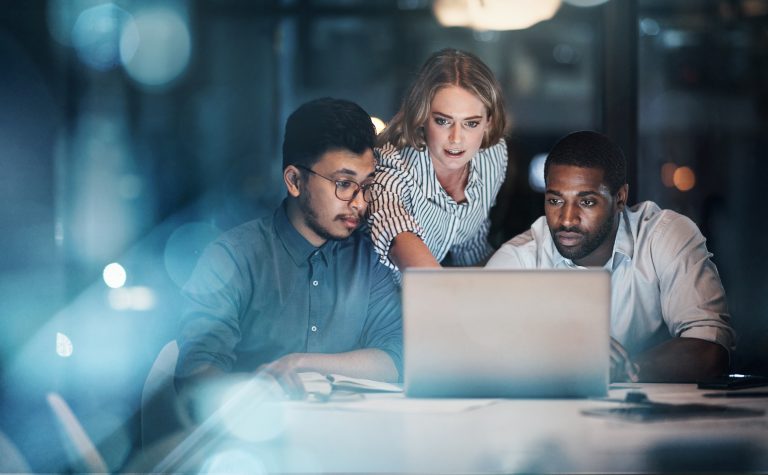 Cropped shot of three young businessmpeople working together on a laptop in their office late at night