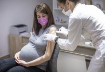 Pregnant woman taking a vaccination against covid-19 virus during pandemic in medical clinic office.