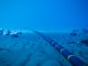 Underwater fiber-optic cable on ocean floor.