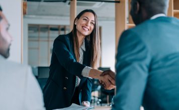 Business people shaking hands in the office. Group of business persons in business meeting. Three entrepreneurs on meeting in board room. Corporate business team on meeting in modern office. Female manager discussing new project with her colleagues. Company owner on a meeting with two of her employees in her office.