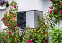 outdoor unit of a heat pump heating system surrounded by flowers